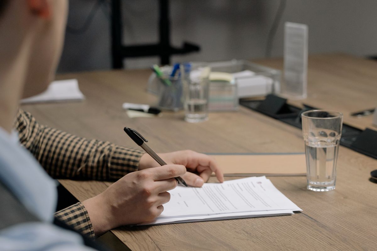 Une personne signe des documents administratifs sur un bureau, comme lors de l'inscription au registre national de l'auto-entrepreneur au Maroc