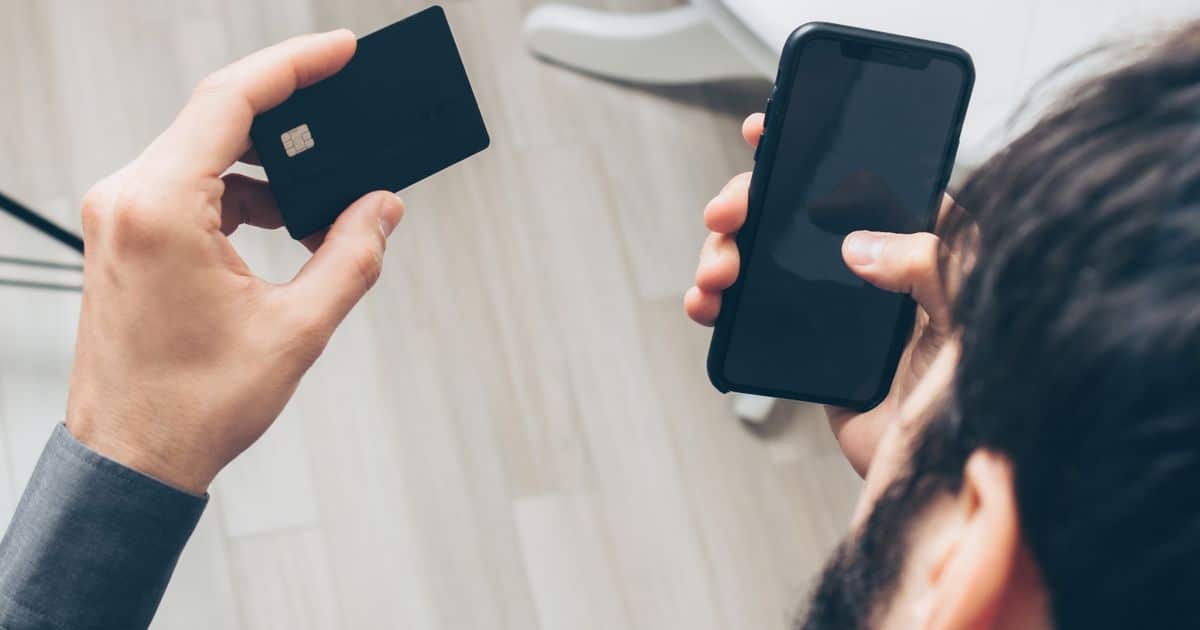 Un freelance effectue un paiement en ligne avec son smartphone et sa carte bancaire